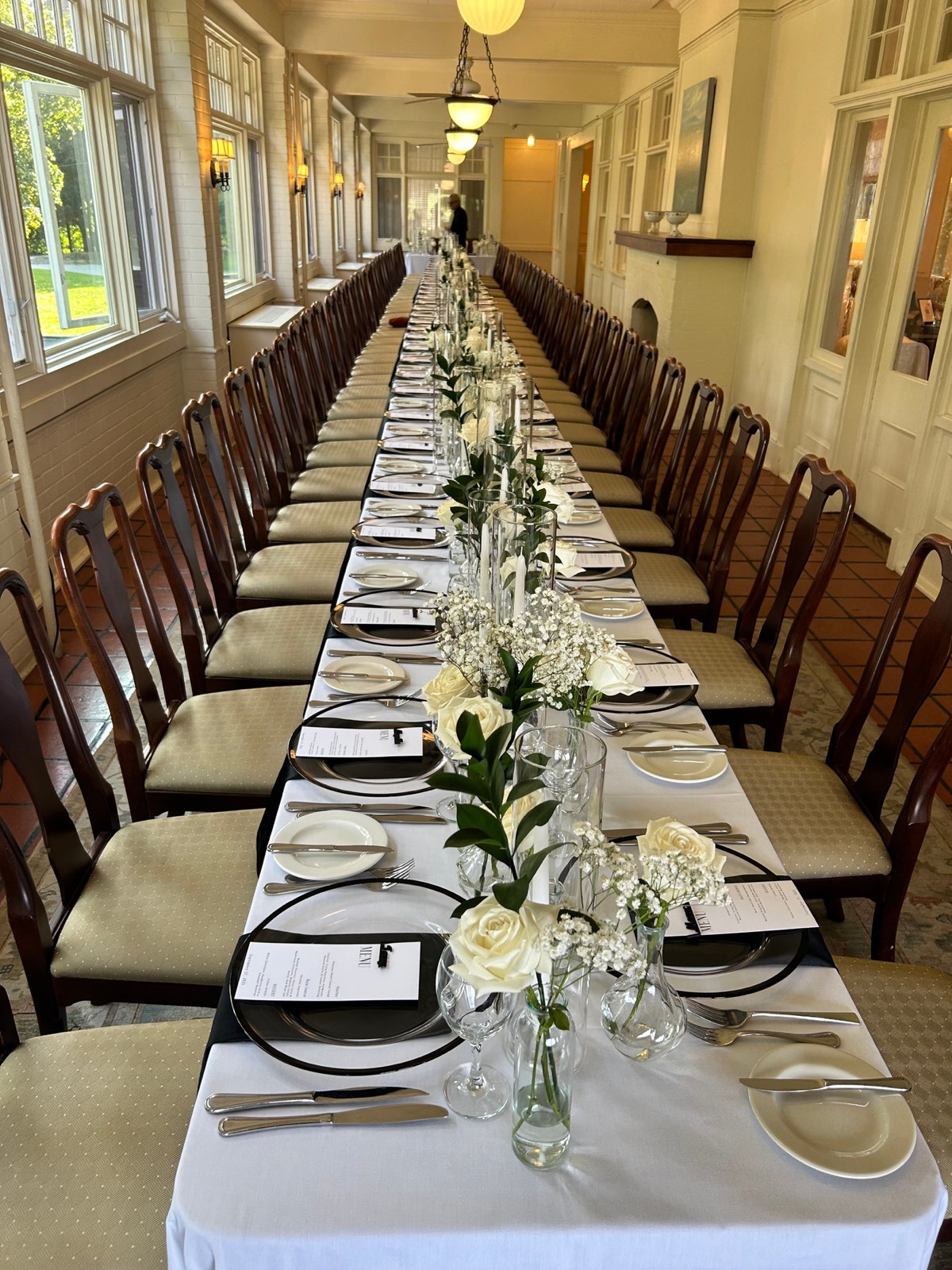 A long banquet table set with white florals and taper candles